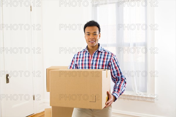 Mixed race man carrying cardboard box in new home