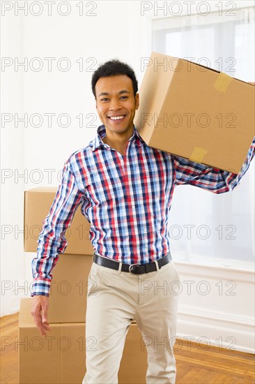 Mixed race man carrying cardboard box in new home