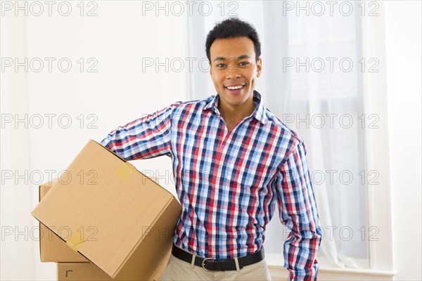 Mixed race man carrying cardboard box in new home