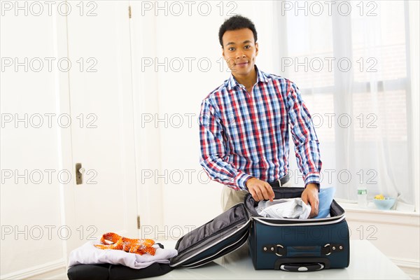 Mixed race businessman packing suitcase