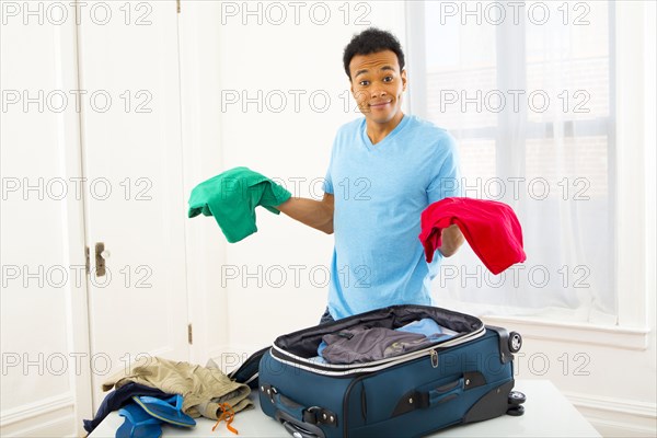 Mixed race man packing suitcase