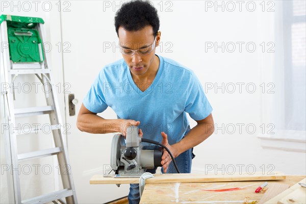 Mixed race carpenter using hand saw