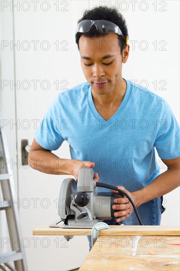 Mixed race carpenter using hand saw