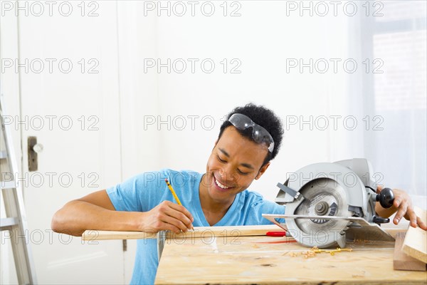 Mixed race carpenter marking wood