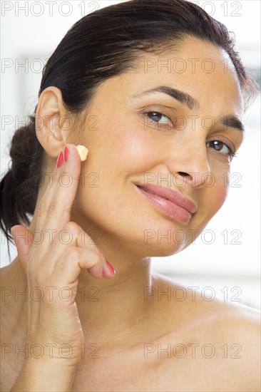 Mixed race woman applying moisturizer