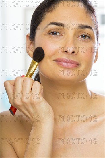 Mixed race woman applying makeup