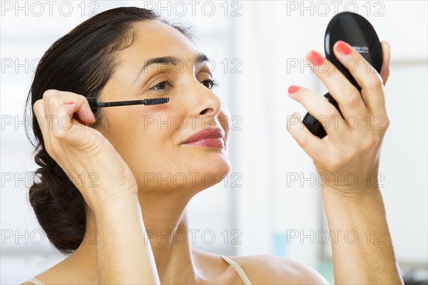 Mixed race woman applying makeup