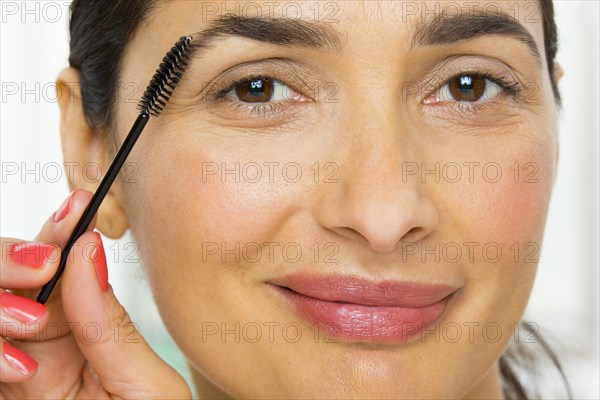 Mixed race woman applying makeup