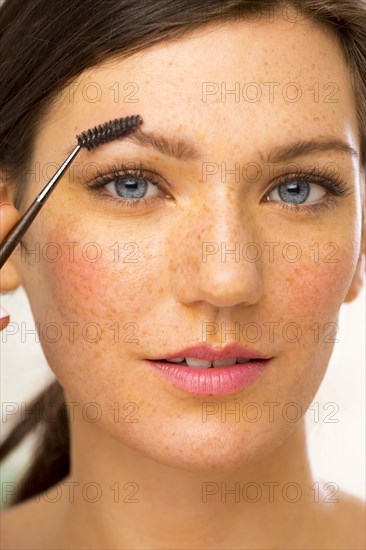 Caucasian woman applying makeup