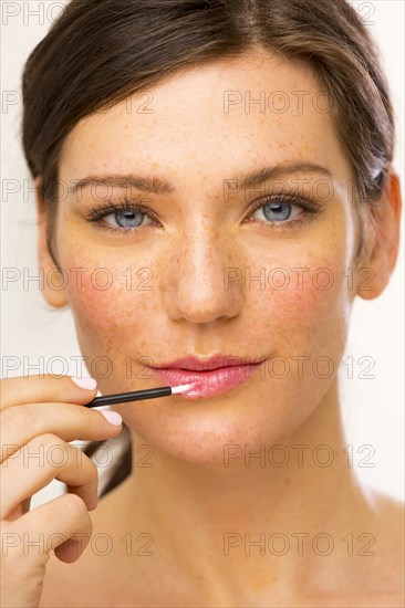 Caucasian woman applying makeup