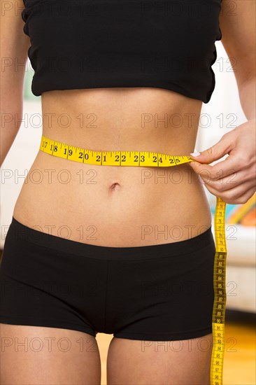 Caucasian woman measuring her waist