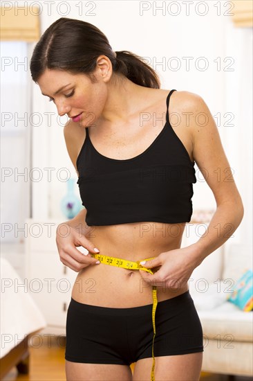 Caucasian woman measuring her waist