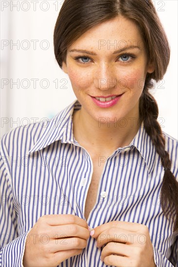 Caucasian woman buttoning shirt