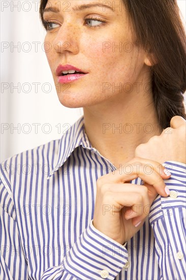 Caucasian woman buttoning shirt cuffs