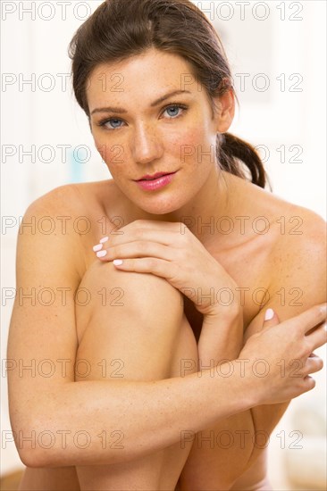 Nude Caucasian woman hugging her knee