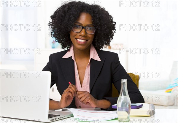 Mixed race businesswoman smiling at desk