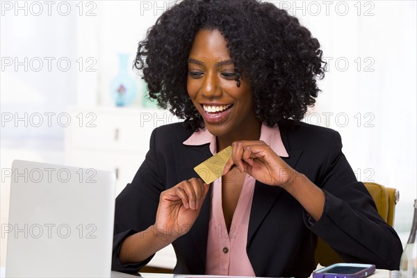 Mixed race businesswoman shopping on laptop at desk