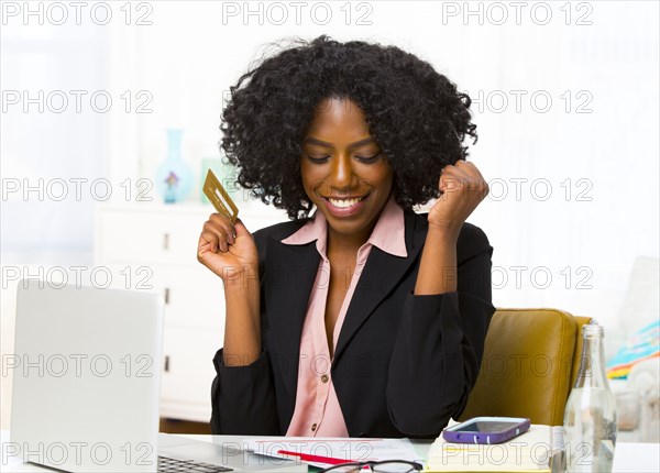 Mixed race businesswoman shopping on laptop at desk