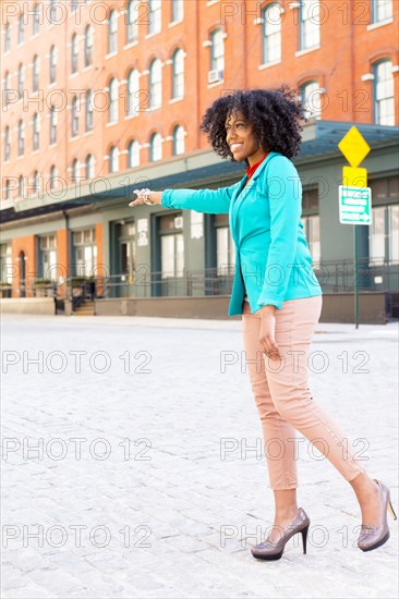 Mixed race woman hailing taxi on city street