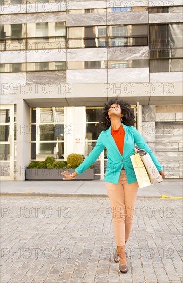 Mixed race woman carrying shopping bags on city street