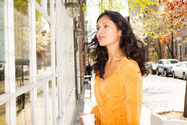 Mixed race woman window shopping on city sidewalk