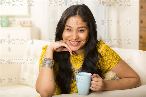 Hispanic woman having cup of coffee