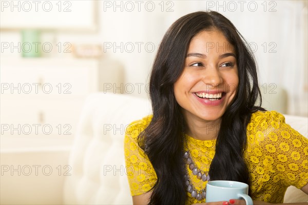 Hispanic woman having cup of coffee