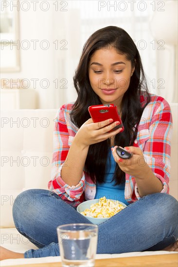 Hispanic woman using cell phone on sofa