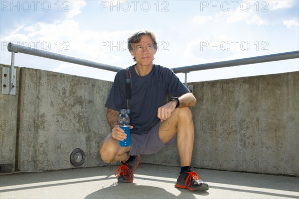 Caucasian runner resting on urban rooftop