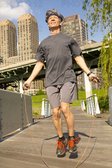 Caucasian man jumping rope in urban park