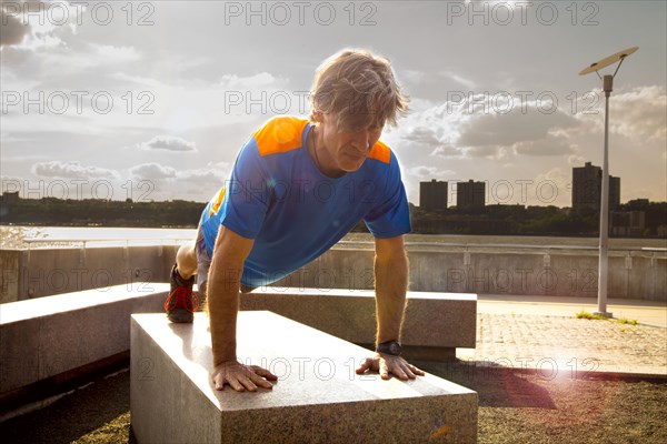 Caucasian man doing push ups in urban park