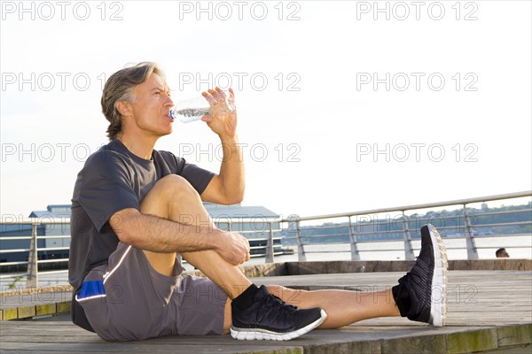 Caucasian runner drinking water in waterfront park