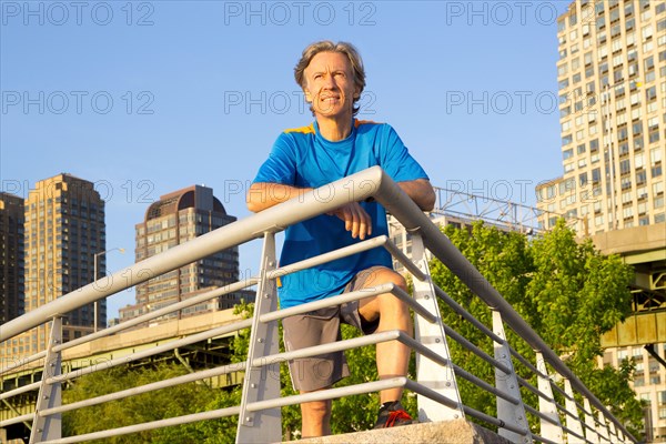 Caucasian man leaning on railing in urban park