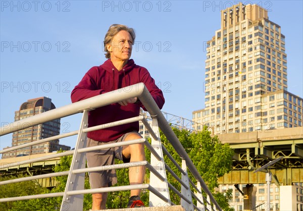 Caucasian man leaning on railing in urban park