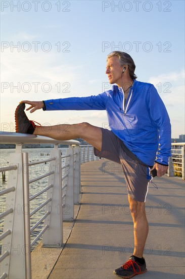 Caucasian runner stretching on urban waterfront