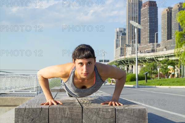 Mixed race woman doing push ups near city street