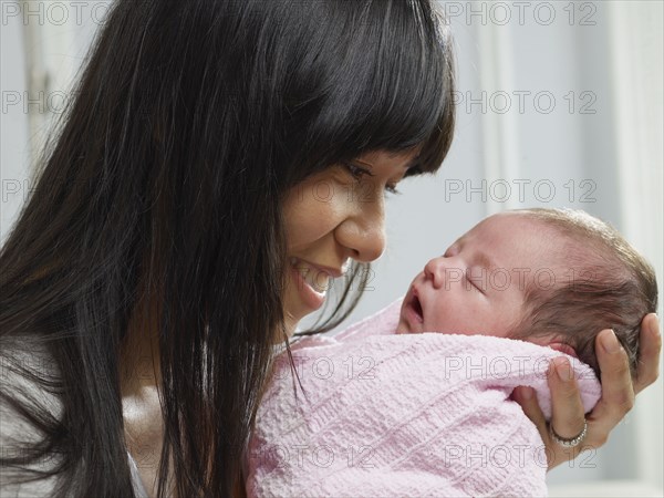 Mixed race mother cuddling newborn baby