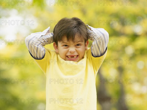 Toothless Hispanic boy smiling outdoors in autumn