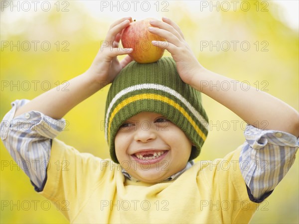 Toothless Hispanic boy balancing apple on head