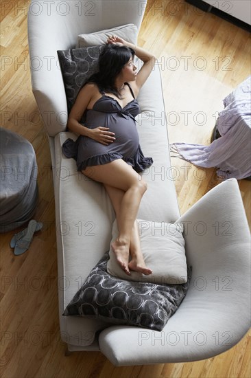 Pregnant mixed race woman relaxing in living room