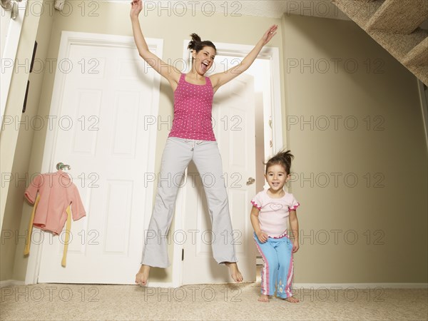 Mother and daughter jumping in house