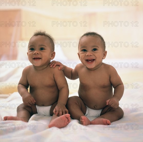 Spanish twin baby boys sitting on blanket