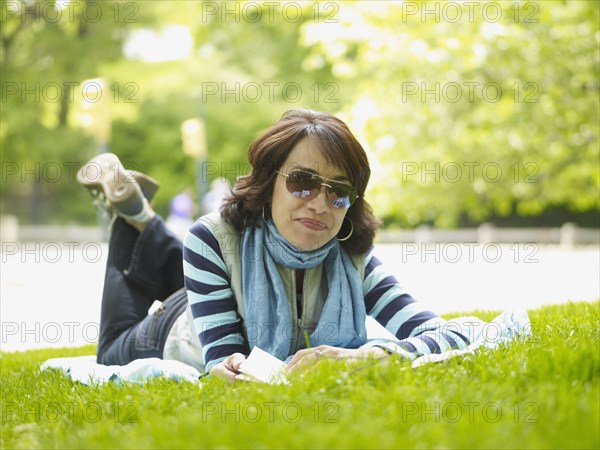 Hispanic woman laying on blanket in grass