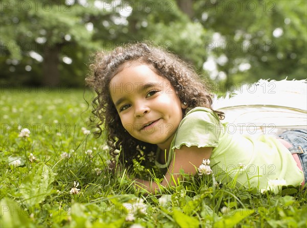 Mixed race girl laying in grass