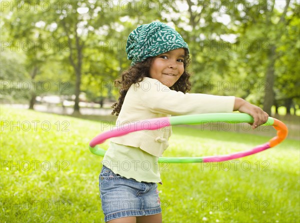 Mixed race girl playing with plastic hoop