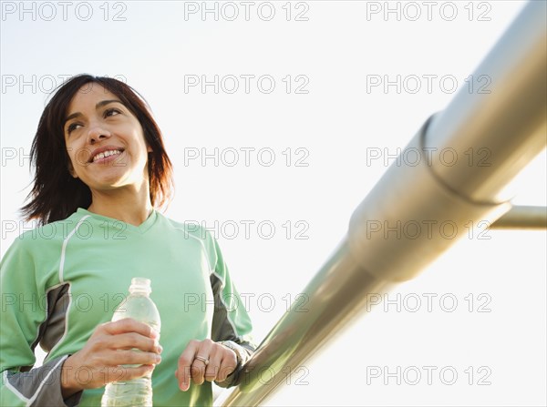 Mixed race woman drinking water by railing