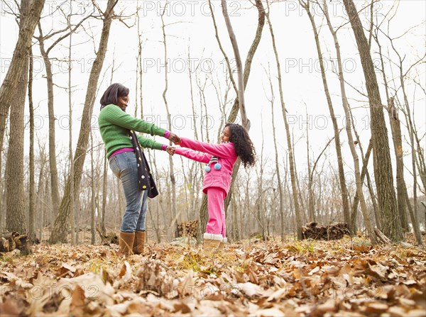 Mother and daughter playing in autumn leaves