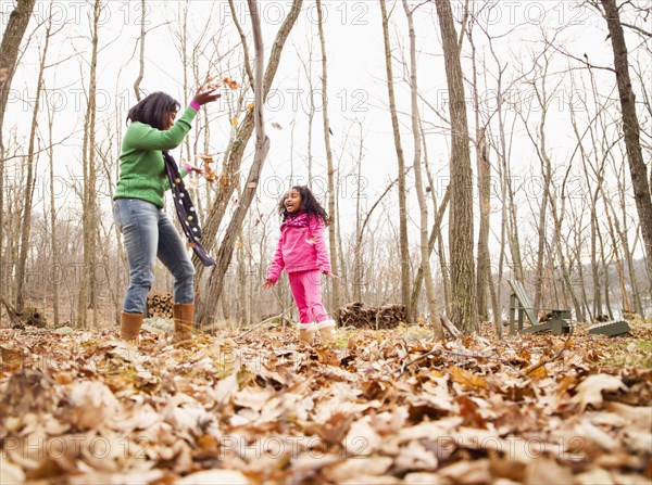 Mother and daughter playing with autumn leaves