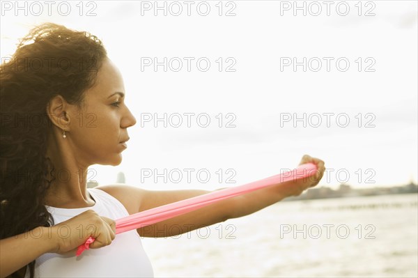 Hispanic woman stretching with resistance band