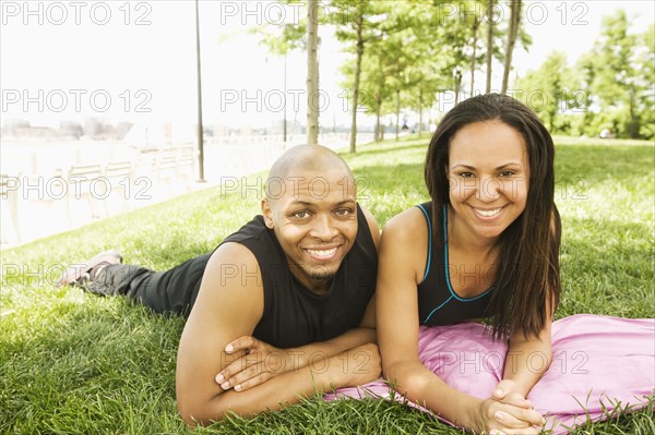 Smiling couple laying in grass at park